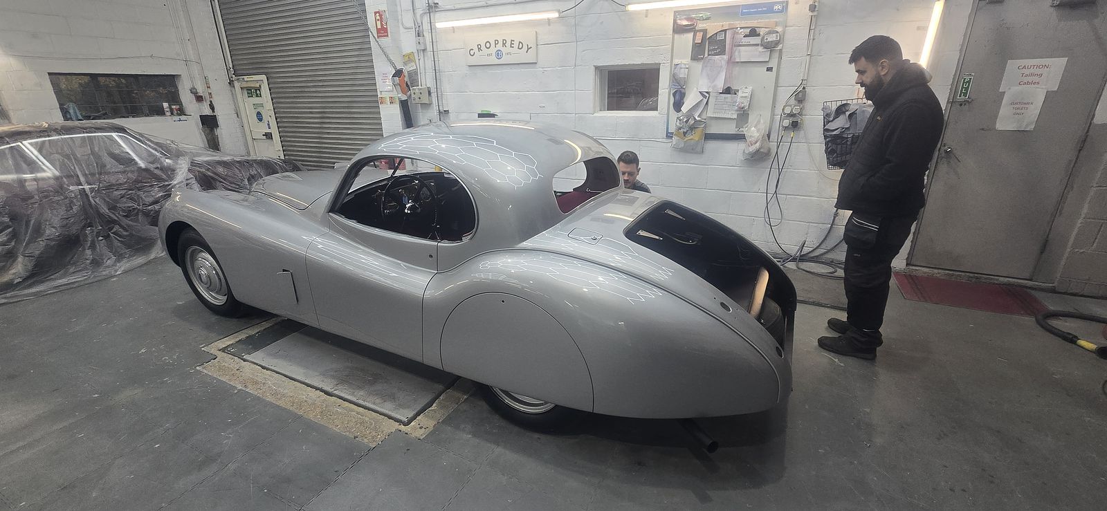 The XK120 Coupé raised on a lift in the workshop