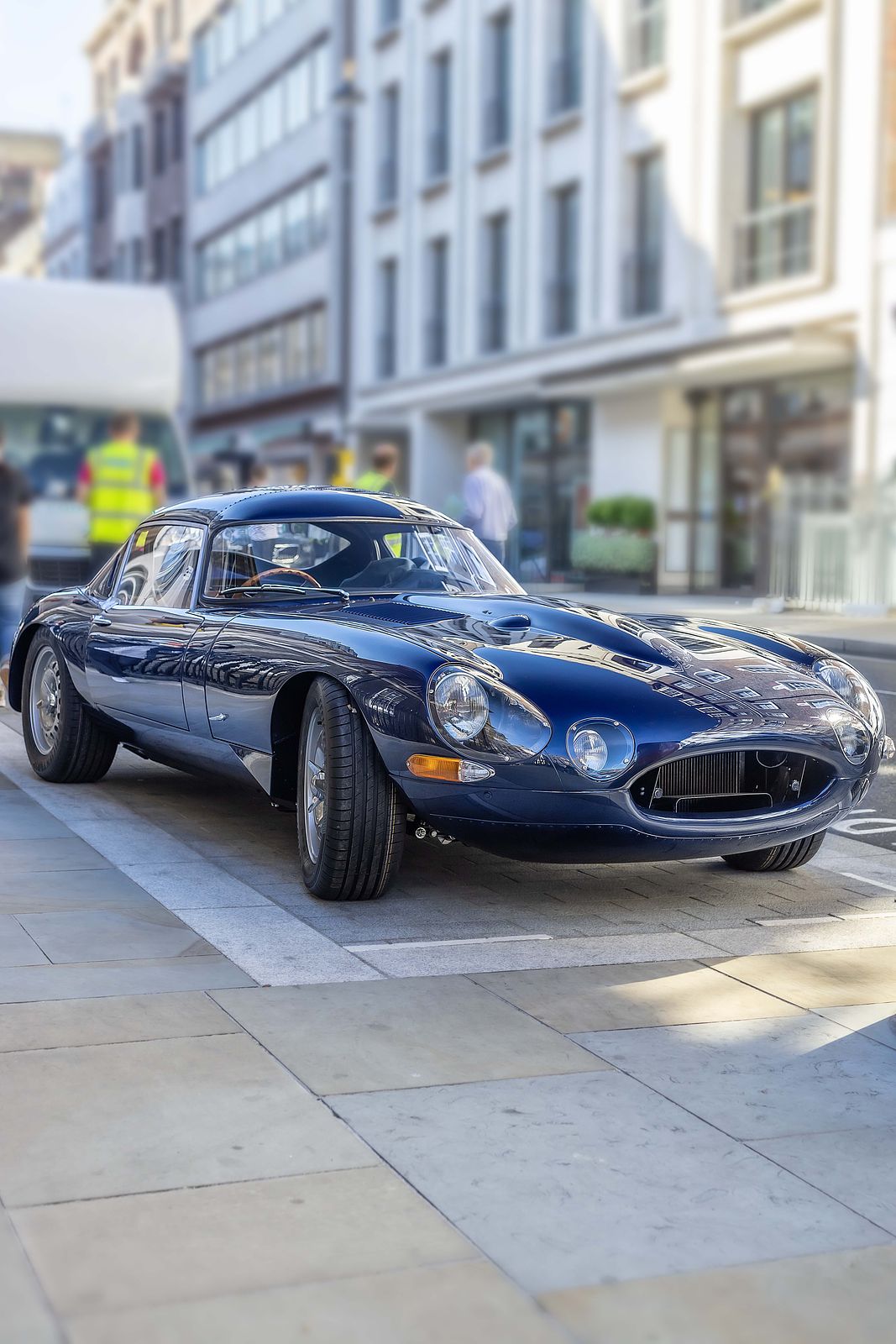 E-Type Re-Imagined — dark blue coupe parked on a city street